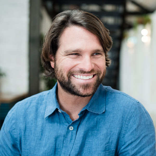 man in jean shirt with beard smiling